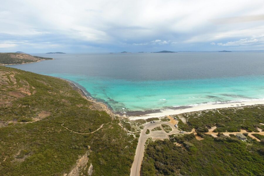 Aerial view of road leading to cleared area for camping close to a beach.