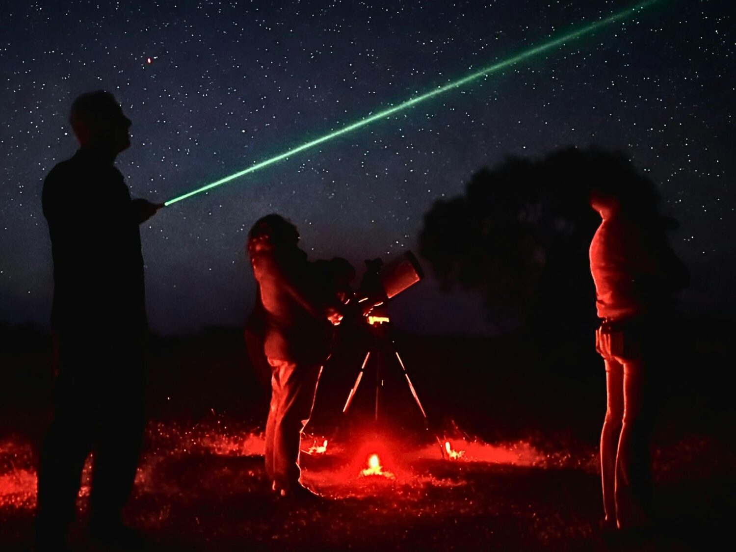 Astronomy guide using a green laser to point out stars as guests observe through a telescope