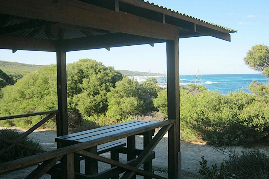 Sheltered picnic table and seat with a view of the ocean.